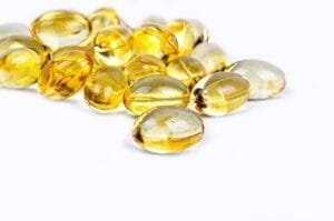 Close-up of translucent golden-yellow Vitamin D gel capsules piled on a white background