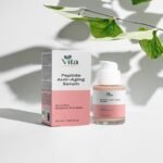 A bottle and box of Vita Elixia Peptide Anti-Aging Serum displayed under the soft shadow of green leaves