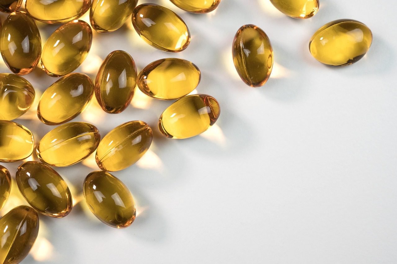 Scattered golden oil softgels on a white surface representing Omega-3 fatty acids and heart health supplements.