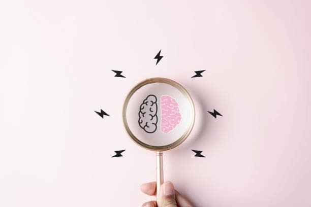 A magnifying glass held over a brain graphic surrounded by lightning bolts