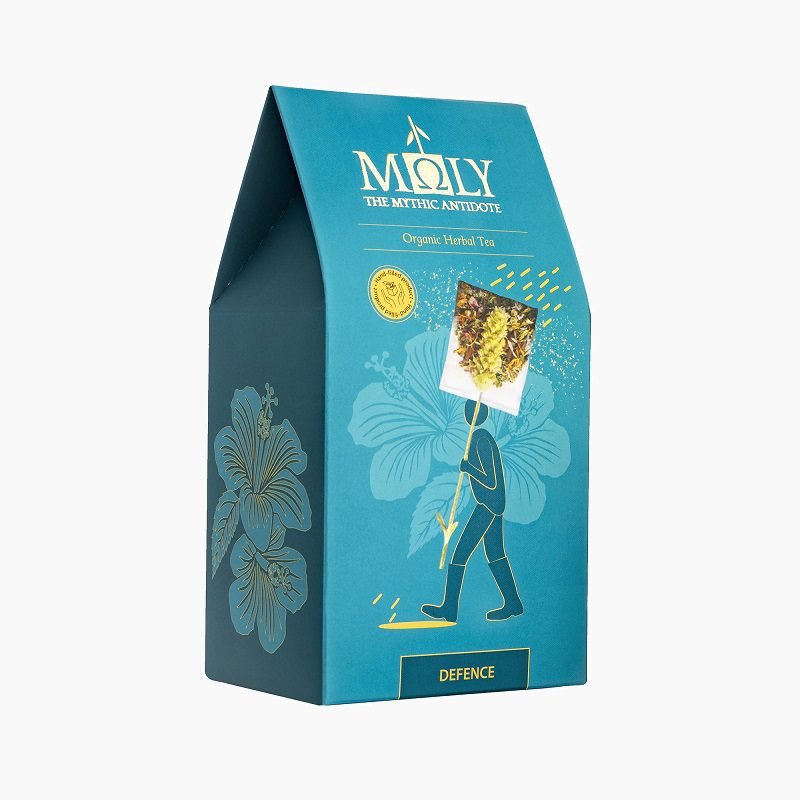 Teal retail box for Moly "Defence" Organic Herbal Tea featuring gold branding and a playful illustration of a figure carrying a large tea bag.