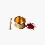 Gold brass mortar and pestle beside a pile of red organic saffron threads