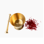 Perspective view of a polished gold brass mortar and pestle next to a pile of red organic saffron threads.