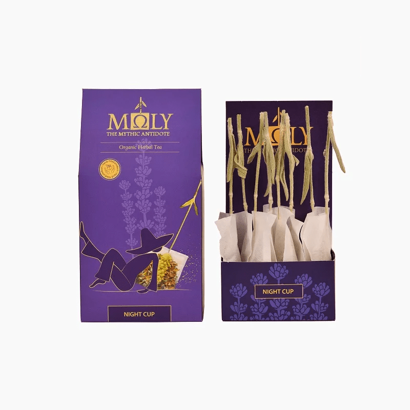 Deep purple retail box for Moly "Night Cup" Organic Herbal Tea shown next to an open display box containing individually wrapped tea bags with natural herbal stem stirrers.
