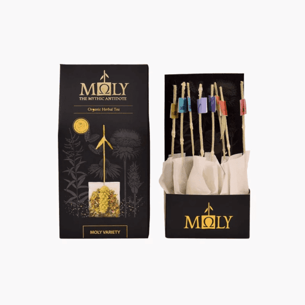 Moly Variety Organic Herbal Tea display showing the black and gold retail box alongside an open package revealing multiple individually wrapped tea bags with long wooden-style stirrers.